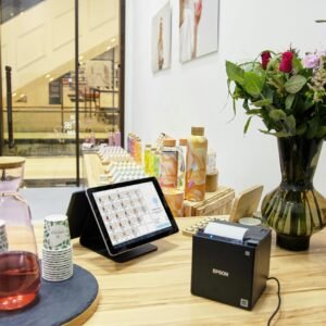 A stylish store checkout counter featuring a floral bouquet and digital payment system.